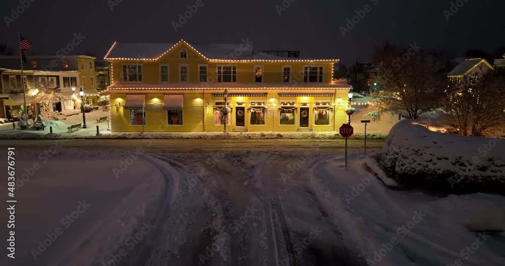 Driver POV approaching stop sign on winter snow street. Yellow Victorian building decorated for Christmas. American flag in breeze. Driver POV approaching stop sign on winter snow street. Yellow Victorian building decorated for Christmas. American flag in breeze.