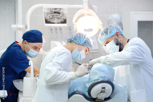 Surgeon and nurse during a dental operation. Anesthetized patient in the operating room. Installation of dental implants in the clinic. photo