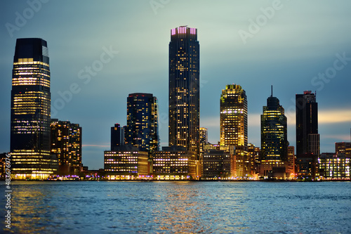 Amazing view of cityscape of New Jersey and Hudson river on blue hour. Landscape with illuminated skyscrapers on twilight. Travel, tourism, sightseeing of USA.