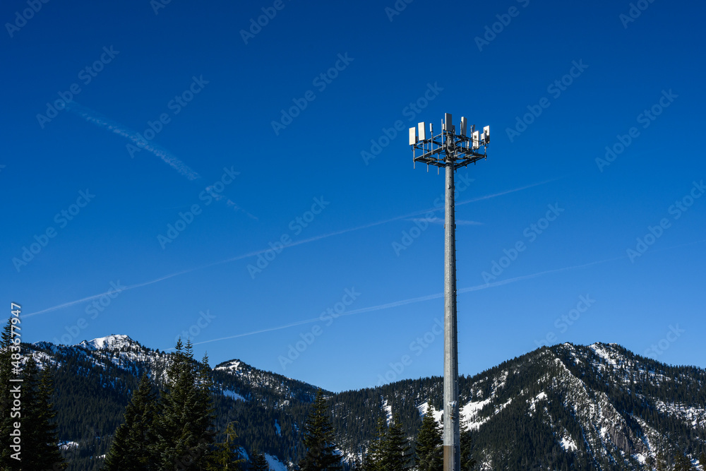 Wireless cell site with antenna mounted on towers in a winter mountain landscape on a sunny day.
