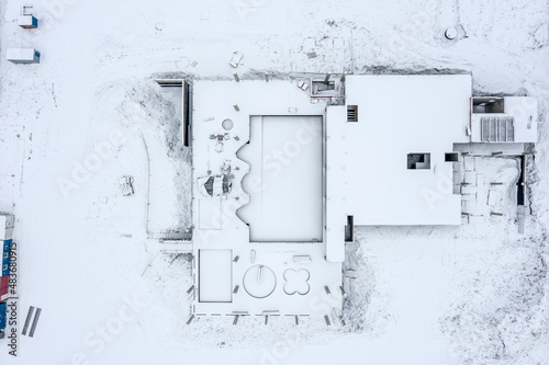 snowy construction site. foundation of new building covered with snow. aerial top view from flying drone.
