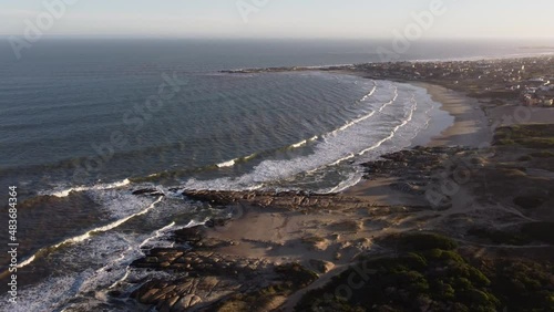 Beautiful aerial shot showing Playa del Rivero during sunset time in Punta del Diablo,Uruguay - Waves of Ocean reaching sandy beach and coastline photo