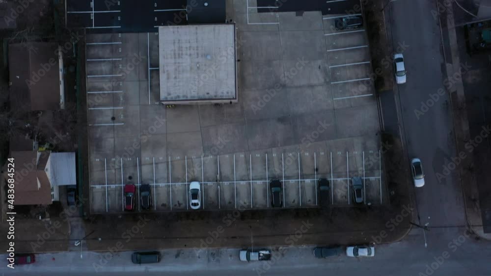 A top down shot over a car dealer at sunset. The chip shortage is causing worldwide automobile industry issues with low inventory levels. The camera looking straight down dolly in over the empty lot. A top down shot over a car dealer at sunset. The chip shortage is causing worldwide automobile industry issues with low inventory levels. The camera looking straight down dolly in over the empty lot.