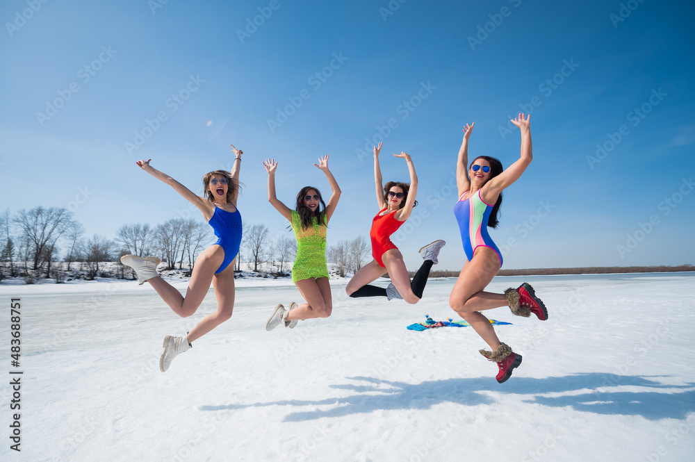 Four Caucasian women in swimsuits are fooling around on a snowy beach. Winter fun. Four Caucasian women in swimsuits are fooling around on a snowy beach. Winter fun.