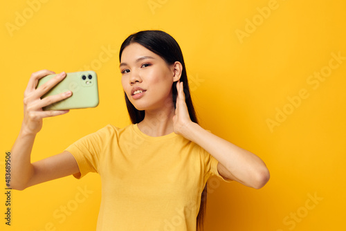 woman with Asian appearance with a smartphone in hands fun emotions close-up studio model unaltered
