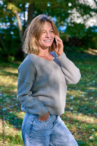 Beautiful woman talking on the phone in the park in summer © Евгений Порохин
