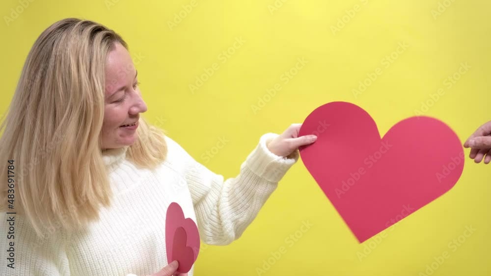 4k. Blond girl accepting a gift in the form of paper heart. Happy smiling woman with a red paper heart in her hands expresses delight and joy. Holiday concept, Valentine's Day, Women's Day, Birthday 4k. Blond girl accepting a gift in the form of paper heart. Happy smiling woman with a red paper heart in her hands expresses delight and joy. Holiday concept, Valentine's Day, Women's Day, Birthday