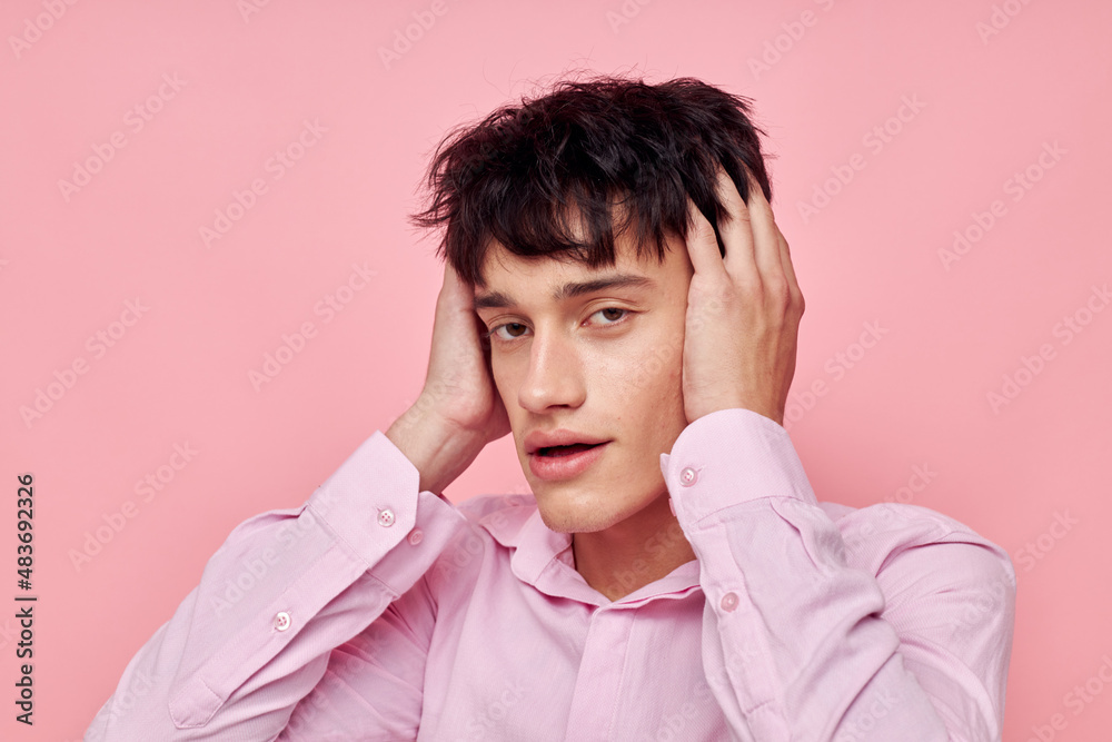 A young man in a pink shirt gesturing with his hands pink background unaltered A young man in a pink shirt gesturing with his hands pink background unaltered
