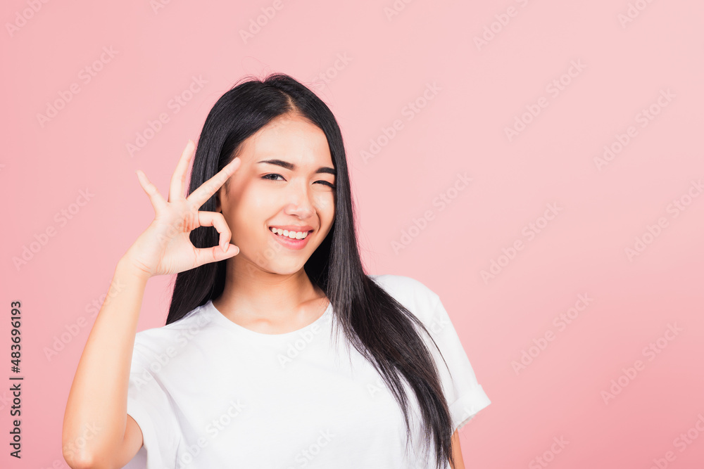 Portrait Asian beautiful young woman made finger OK symbol sign gesture wink eyes to agree and looking at camera, studio shot isolated on pink background, Thai female agree hand sign copy space Portrait Asian beautiful young woman made finger OK symbol sign gesture wink eyes to agree and looking at camera, studio shot isolated on pink background, Thai female agree hand sign copy space