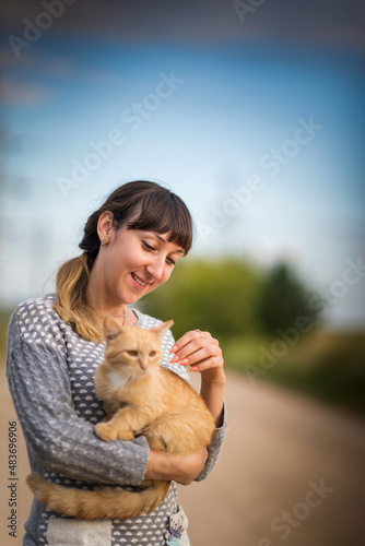 Portrait of a young beautiful dark-haired girl with a cat in her arms.