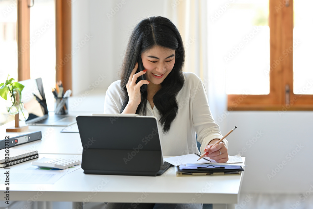 Portrait with confident businesswoman talking on smartphone while sitting at the office, Business and financial concept. Portrait with confident businesswoman talking on smartphone while sitting at the office, Business and financial concept.