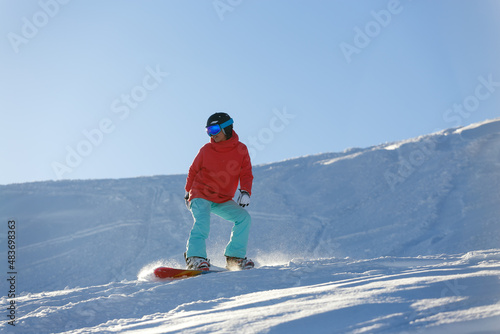Girl snowboarder rolls down the mountain on a snowboard