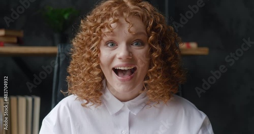 Close-up portrait of excited young woman student with red hair very glad, showing wow emotion at office background