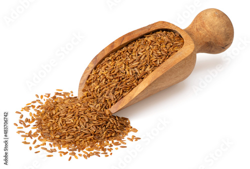 Roasted cumin seeds in the wooden scoop, isolated on the white background.