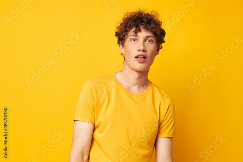 Young curly-haired man wearing stylish yellow t-shirt posing Lifestyle unaltered © Tatiana