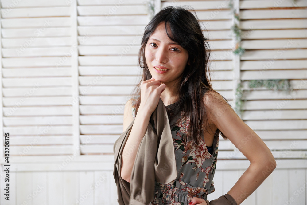 おしゃれな背景の前でポーズをする袖なしワンピースの日本人女性 おしゃれな背景の前でポーズをする袖なしワンピースの日本人女性