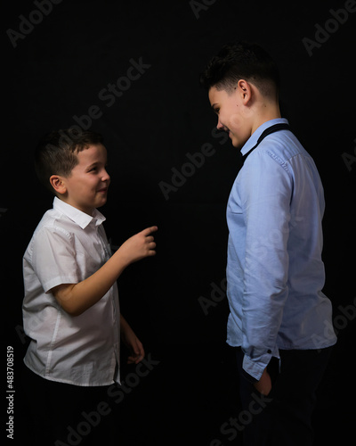 Two boys on a black background are brothers.Senior and junior.Atelier.proof