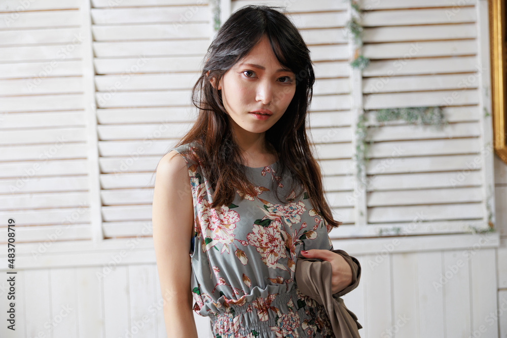 おしゃれな背景の前でポーズをする袖なしワンピースの日本人女性 おしゃれな背景の前でポーズをする袖なしワンピースの日本人女性