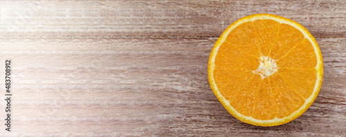 Half an orange on a wooden table. Banner with orange. Orange on a wooden background.