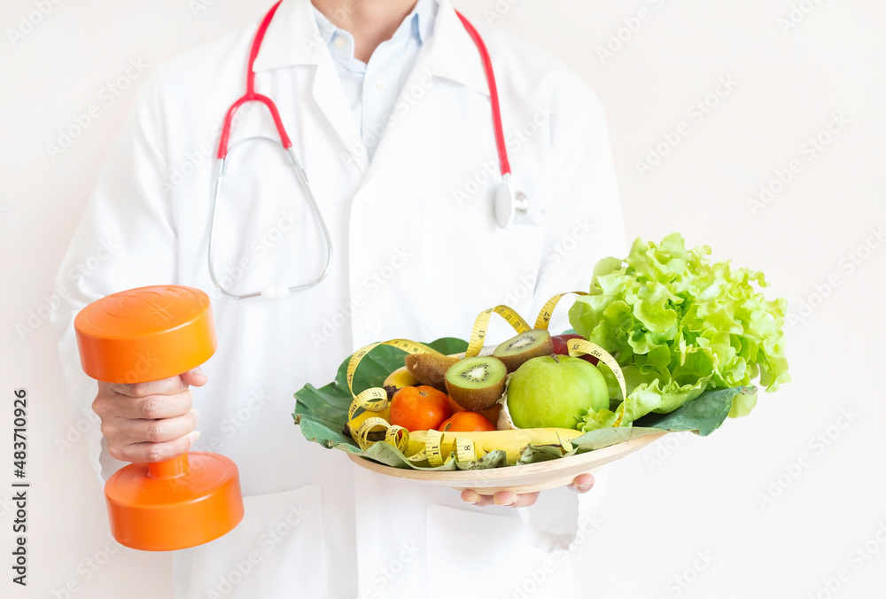 Selective focus of Doctor hand with tray of a healthy foods and dumbbell ,check a healthy eating ,workout and fitness dieting ,fitness and weight loss concept Selective focus of Doctor hand with tray of a healthy foods and dumbbell ,check a healthy eating ,workout and fitness dieting ,fitness and weight loss concept