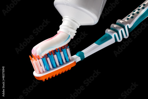 toothbrush and tube of toothpaste on black background