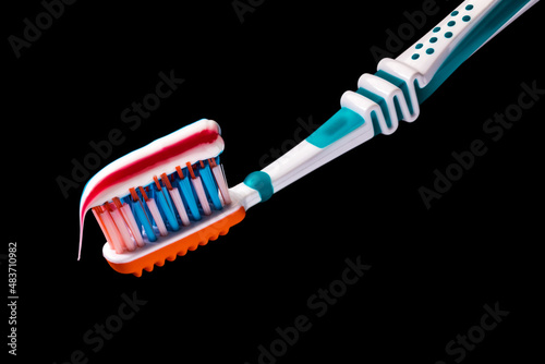 toothbrush with multicolored toothpaste on it isolated on black background