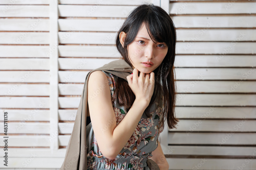 おしゃれな背景の前でポーズをする袖なしワンピースの日本人女性 おしゃれな背景の前でポーズをする袖なしワンピースの日本人女性