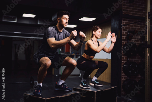 Принти на полотні A dedicated sporty couple doing squats in a gym and practicing functional exercises