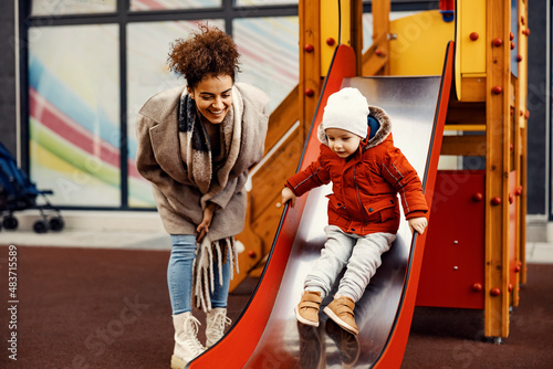 A nanny babysitting a little boy at the playground. 