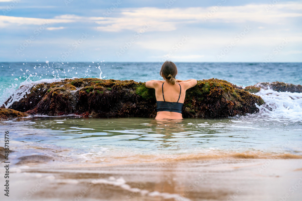 Woman looking to ocean on Secret Jimbaran beach, Bali, Indonesia
