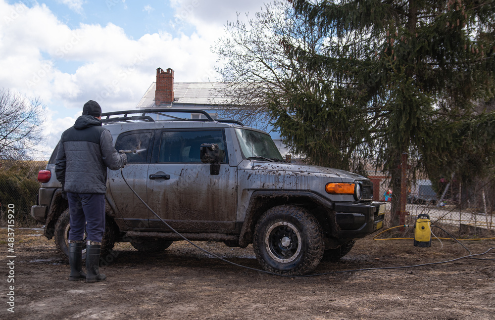 Obraz premium a man washes his dirty car in the yard of his house