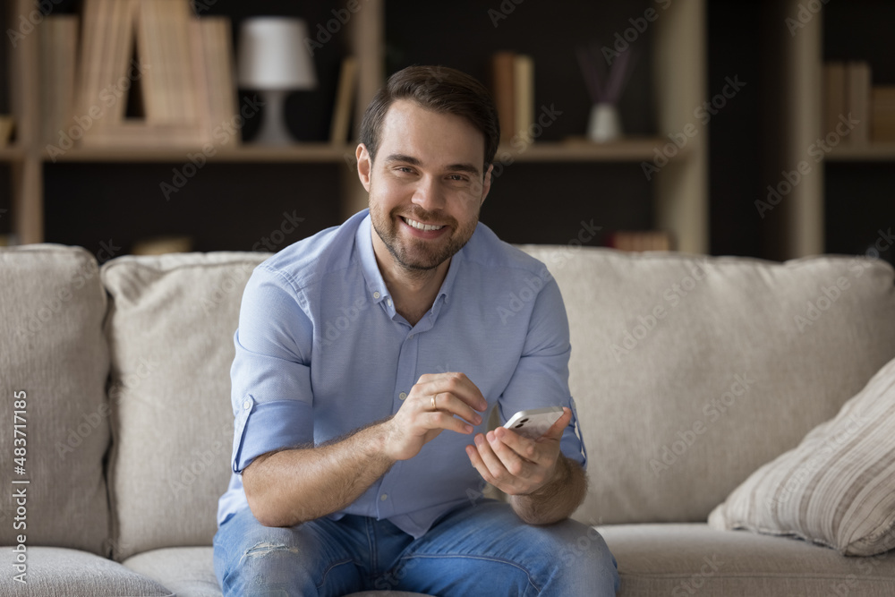 Portrait of smiling relaxed young man holding cellphone in hands, enjoying web surfing information, using mobile software apps, choosing goods shopping online, watching funny photo video content. Portrait of smiling relaxed young man holding cellphone in hands, enjoying web surfing information, using mobile software apps, choosing goods shopping online, watching funny photo video content.