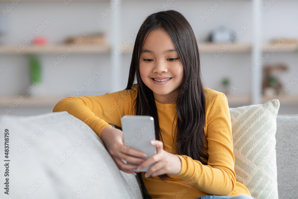 Cute asian girl schooler playing games on cellphone, panorama Cute asian girl schooler playing games on cellphone, panorama