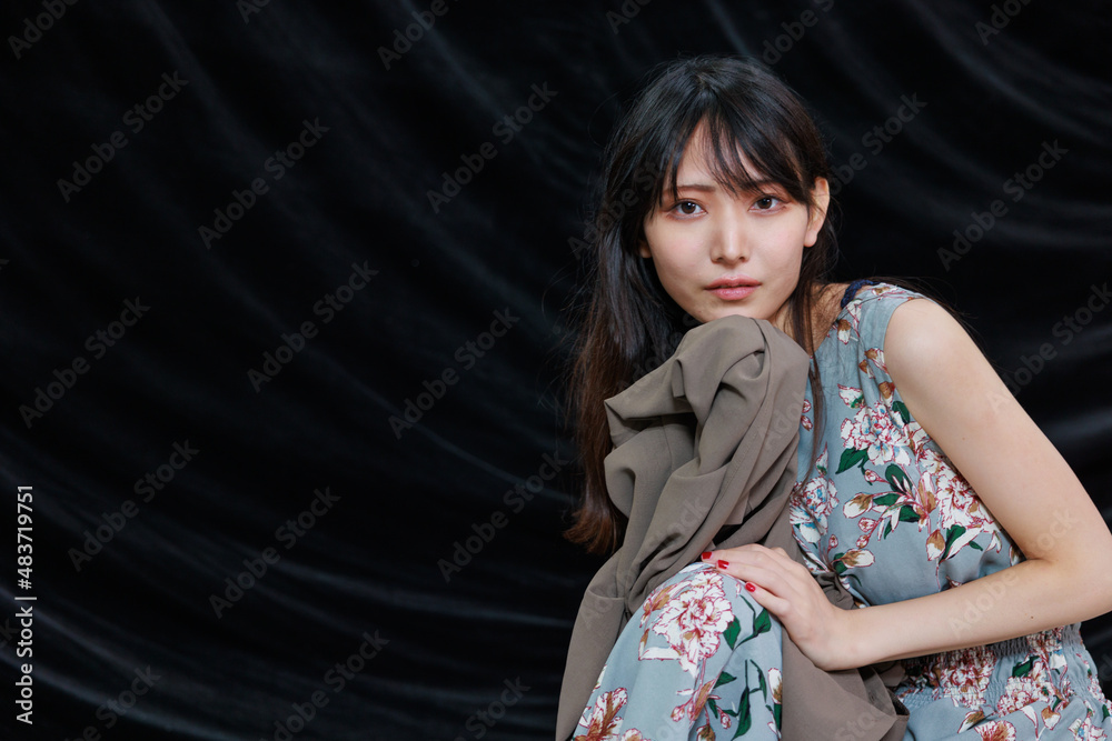 Naklejka premium カメラ目線のアジア人女性と黒背景