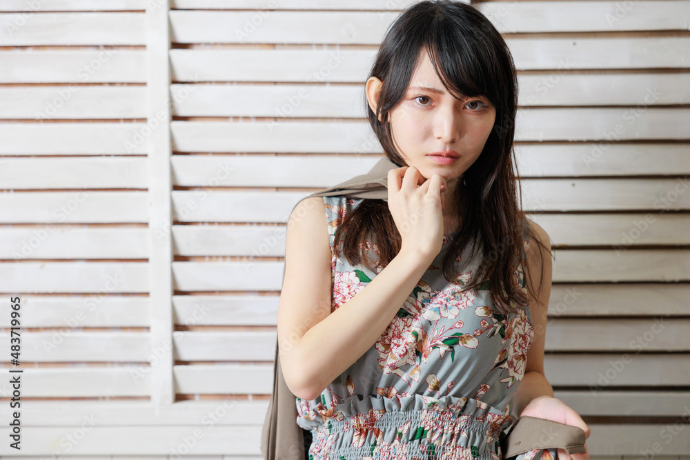 おしゃれな背景の前でポーズをする袖なしワンピースの日本人女性 おしゃれな背景の前でポーズをする袖なしワンピースの日本人女性