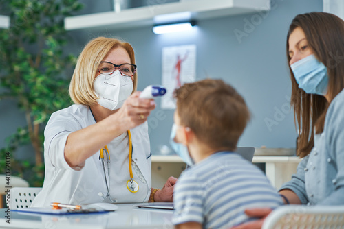 Pediatrician doctor examining little kids in clinic temperature check