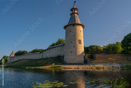 View of the wall of the Pskov Kremlin and High (Vysokaya) tower on the bank of the Pskova River on a sunny summer day, Pskov, Russia