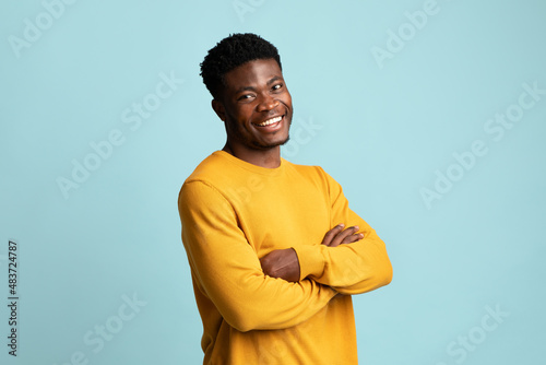 Positive young black man posing on blue