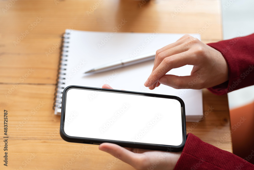 Woman sitting using a smartphone blank white screen at the office. Mock up. Woman sitting using a smartphone blank white screen at the office. Mock up.