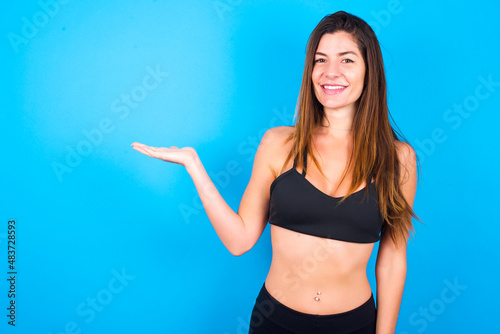 Positive glad Young beautiful sportswoman doing sport wearing sportswear says: wow how exciting it is, has amazed expression, shows something on blank space with open hand. Advertisement concept.