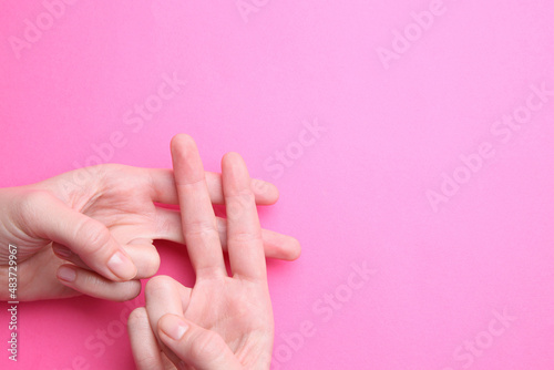Woman making hashtag symbol with her hands on pink background, top view. Space for text