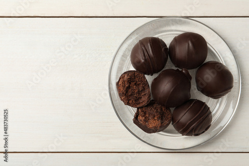 Many delicious chocolate truffles on white wooden table, top view. Space for text