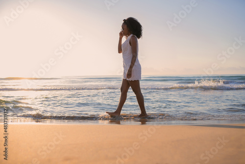 African american woman walking along the beach at sunset © JeanPaul