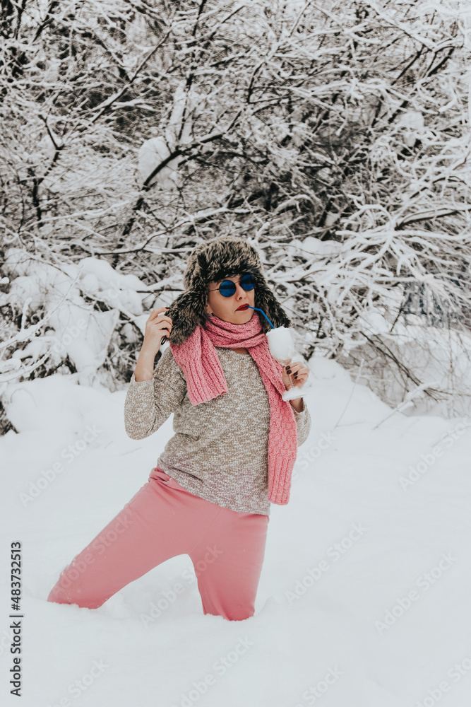 Young woman in sunglasses and a wine glass filled with snow. Woman misses relaxing on the beach Young woman in sunglasses and a wine glass filled with snow. Woman misses relaxing on the beach