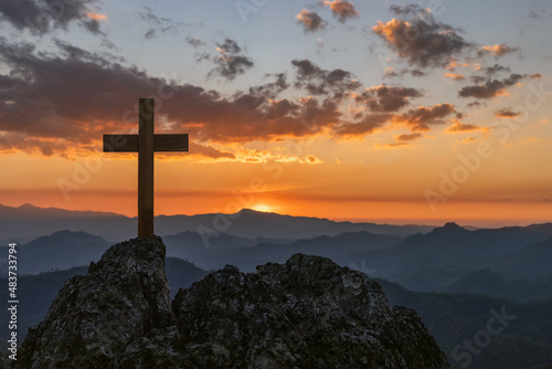 Silhouettes of crucifix symbol on top mountain with bright sunbeam on the colorful sky background