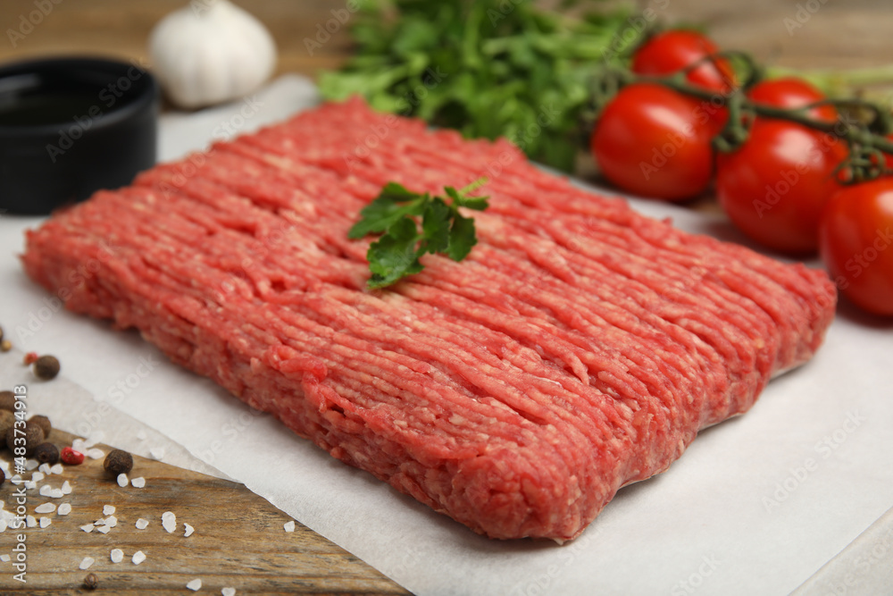 Raw fresh minced meat, tomatoes and other ingredients on wooden table. Space for text Raw fresh minced meat, tomatoes and other ingredients on wooden table. Space for text