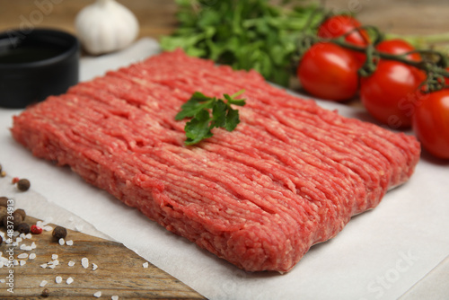 Raw fresh minced meat, tomatoes and other ingredients on wooden table. Space for text