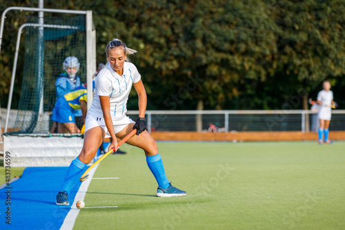 Young woman performing penalty shot in field hockey game.