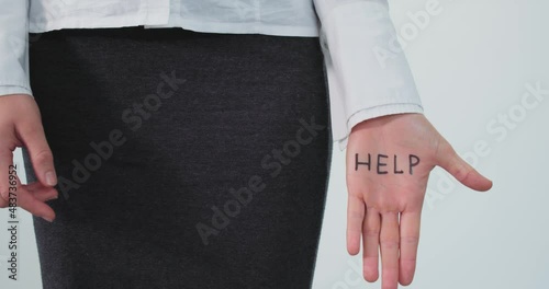 Female figure secretly asking for help wearing office clothes showing her hand with word HELP written on it photo