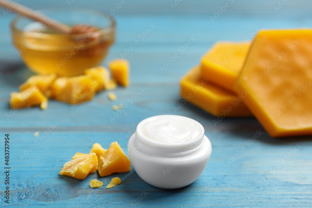 Cream with natural beeswax component on blue wooden table Cream with natural beeswax component on blue wooden table